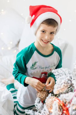 Evdeki Noel ağacının yanında gülümseyen ve gülen neşeli çocuğun portresi. Aileler ve çocuklar, kış tatilini kutlayan alfa nesli..