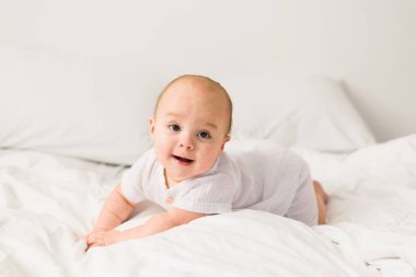 Bebek çocuk beyaz güneşli yatak odasında. Yeni doğan çocuk yatakta rahatlatıcı. Genç çocuklar için kreş. Tekstil ve çocuklar için yatak. Aile sabah evde