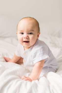 Bebek çocuk beyaz güneşli yatak odasında. Yeni doğan çocuk yatakta rahatlatıcı. Genç çocuklar için kreş. Tekstil ve çocuklar için yatak. Aile sabah evde