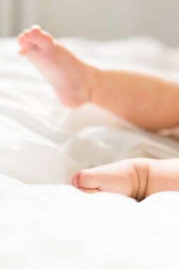 Yatak odası manzaralı, beyaz battaniyeli yeni doğmuş bebek ayakları. Çocuk ve masumiyet.