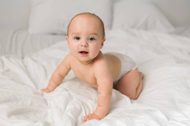 Evdeki beyaz yatakta gülümseyen yeni doğmuş bebek, sağlıklı bebek konsepti. Alfa ve alfa jenerasyonu..