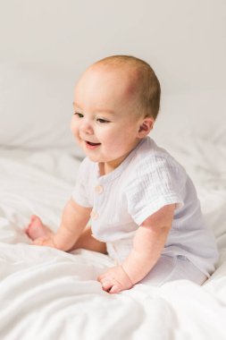 Evdeki beyaz yatakta gülümseyen yeni doğmuş bebek, sağlıklı bebek konsepti. Alfa ve alfa jenerasyonu..