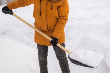 Bir adam soğuk bir günde evin önündeki karları temizler ve temizler. Kış günü sokakları kardan temizlemek. Kışın şiddetli kar yağışı ve şiddetli kar fırtınası