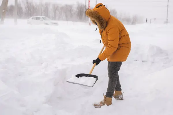 Man cleaning snow from sidewalk and using snow shovel. Winter season.