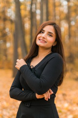 Güzel Hintli kadın nesli z sonbahar parkında rahatlıyor ve doğayı hissediyor. Çeşitlilik ve gen z gençliği.