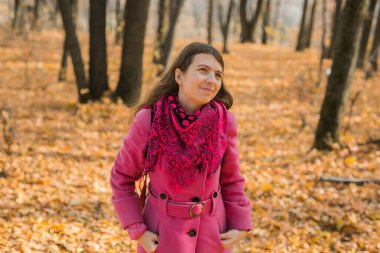 Güz parkında poz veren uzun saçlı, siyah şapkalı ve pembe ceketli güzel, mutlu bir kız. Açık hava portresi gün ışığı. Sonbahar moda konsepti. Metin için boş alanı kopyala.