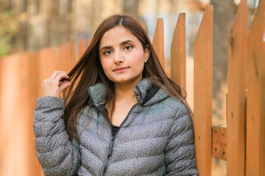 Sonbaharda, kendine güveni tam, genç bir Hintli kadının açık havada çekilmiş portresi. Mutlu ve doğal gülümseyen bir kadın. Z ve Z jenerasyonu gençliği