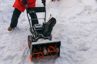 Arka bahçeden kar püskürtücüsüyle kar temizleyen bir adam. Kış mevsimi ve kar temizleme ekipmanları.
