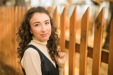 Sonbahar mevsiminde güzel, mutlu, kıvırcık bir kadının sonbahar portresi. Milenyum kuşağı dişisi. Doğal güzellik.