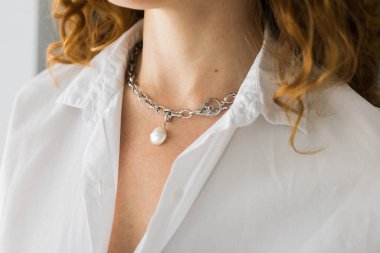 Güzel, lüks bir kolye takan yakın plan bir kadın. El yapımı mücevherler ve aksesuarlar..