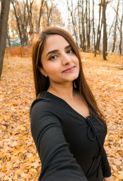 Close-up portrait of a young beautiful confident Indian Asian woman in fall outdoor. Happy and natural smiling female. Generation z and gen z youth
