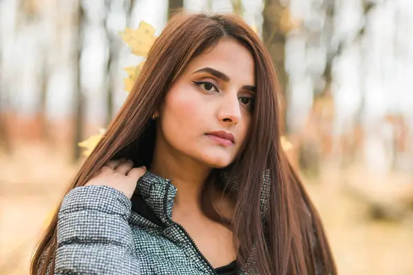 Close-up portrait of a young beautiful confident Indian Asian woman in fall outdoor. Happy and natural smiling female. Generation z and gen z youth