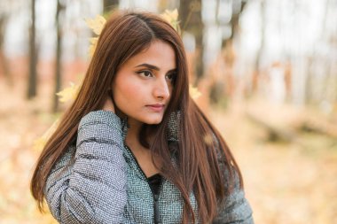 Güzel Hintli kadın nesli z sonbahar parkında rahatlıyor ve doğayı hissediyor. Çeşitlilik ve gen z gençliği.