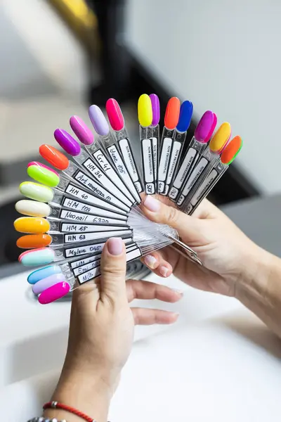 Collection of nails color polish samples. A palette of nail designs of different colors with gel polish. Transparent tips with nail polish samples. Demonstration fan-shaped palette of color shades