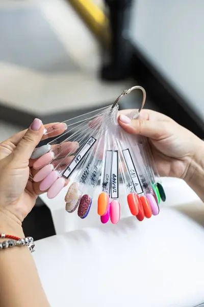 Collection of nails color polish samples. A palette of nail designs of different colors with gel polish. Transparent tips with nail polish samples. Demonstration fan-shaped palette of color shades