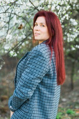 Çiçek açan bahar ağaçları sokağının yanındaki güzel kızıl saçlı kadın. Gençlik ve aşk, moda ve romantik ve yaşam tarzı konsepti