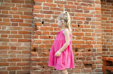 İşitme cihazı ve koklear implantları olan çocuk dışarıda eğleniyor, konuşuyor ve oynuyor. Reklam alanı ve boş yeri kopyala.