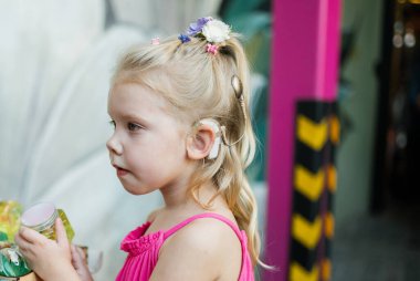 Yaz caddesinde koklear implant işitme cihazıyla yürüyen bir çocuk. İşitme kaybını tedavi etmek için modern teknolojiler.
