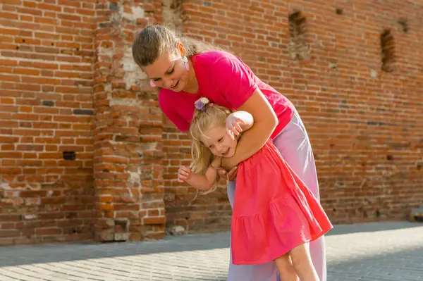 Stock image Deaf child with cochlear implant for hearing audio and aid for impairment having fun and laughs with mother outdoor in summer. Sound fitting device to help with communication listening and interaction