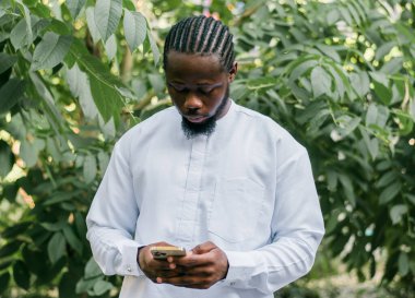 Milenyum kuşağı Afro-Amerikan erkeği açık havada internet konsepti yazıyormuş. Telefonda yüksek hızlı internet, sosyal ağlarda sohbet ve blog