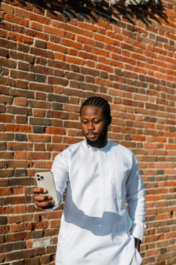 Dashiki etnik kıyafetleri içinde, duvarın arkasında selfie çeken mutlu Afrikalı genç bir Amerikalı. Milenyum kuşağı öğrencisi ve genç