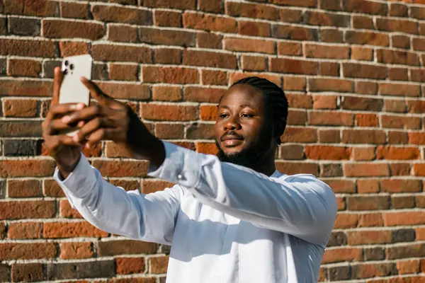 Dashiki etnik kıyafetleri içinde, duvarın arkasında selfie çeken mutlu Afrikalı genç bir Amerikalı. Milenyum kuşağı öğrencisi ve genç