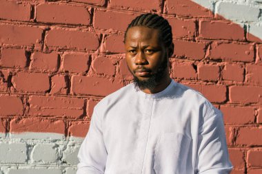 Afrika kökenli mutlu bir Amerikalının dış duvarda etnik Dashiki kıyafetleri giymiş gülümseyen portresi. Milenyum kuşağı öğrencisi ve genç. Boşluğu kopyala.