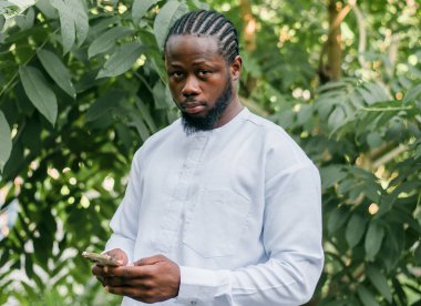 Afrikalı Amerikalı yaz günü sokak kafesinde cep telefonlarını kontrol eder. Milenyum jenerasyonu ve Z jenerasyonu insanları. Sosyal ağlar ve randevu uygulaması