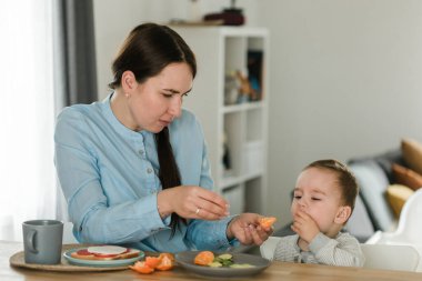 Genç anne bebek oğlu meyve püresi ile besleme