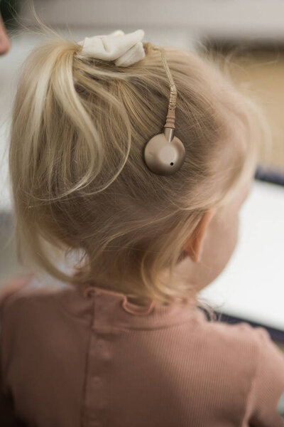 Смешной ребенок с кохлеарным имплантом сидит дома и ест. Услышать помощь и медицина инновационных технологий и разнообразия концепции