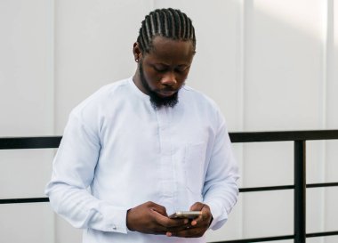 Afrika kökenli Amerikalı şık etnik Dashiki 'li bir adam açık havada boş zamanların tadını çıkarırken sosyal ağlarda fotoğraf çektiriyor. Koyu tenli adam akıllı telefondan ve sosyal ağlardan komik videolar izliyor.