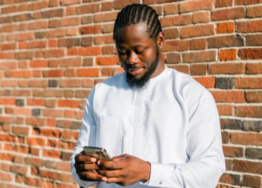 Milenyum kuşağı Afro-Amerikan erkeği açık havada internet konsepti yazıyormuş. Telefonda yüksek hızlı internet, sosyal ağlarda sohbet ve blog