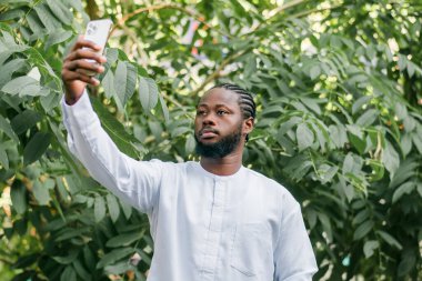 Dashiki etnik kıyafetleri içinde, duvarın arkasında selfie çeken mutlu Afrikalı genç bir Amerikalı. Milenyum kuşağı öğrencisi ve genç