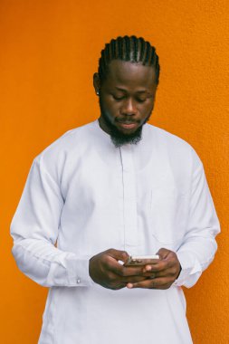 Afrika kökenli Amerikalı şık etnik Dashiki 'li bir adam açık havada boş zamanların tadını çıkarırken sosyal ağlarda fotoğraf çektiriyor. Koyu tenli adam akıllı telefondan ve sosyal ağlardan komik videolar izliyor.