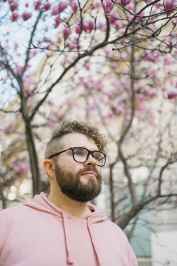 İlkbahar konsepti. Magnolia 'nın arka planındaki sakallı adam. Bahar güzellik sezonu. Botanik ve doğa. Mutlu bahar konsepti. Hippi adam çiçek aromasını sever..