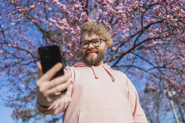 Heureux Bouclé Homme Prend Selfie Sur Fond Arbre Fleurs Printemps Images De Stock Libres De Droits
