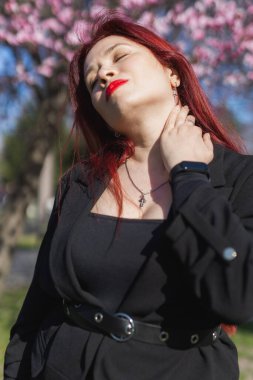 Etrafı çiçek açan ağaçlarla çevrili kiraz çiçekli kadın boşluğu kopyalıyor. Güzellik ve mevsimsel değişim ve bahar mevsimi konsepti