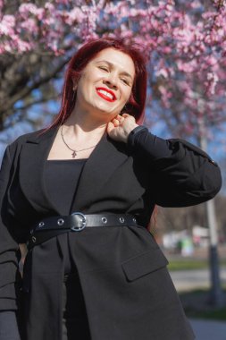 Etrafı çiçek açan ağaçlarla çevrili kiraz çiçekli kadın boşluğu kopyalıyor. Güzellik ve mevsimsel değişim ve bahar mevsimi konsepti