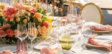 Düğün. Ziyafet. Konuklar, yuvarlak masa ve sandalyeler çatal bıçak takımı, çiçekler ve çanak çömlek ile servis ve bir masa örtüsü ile kaplı