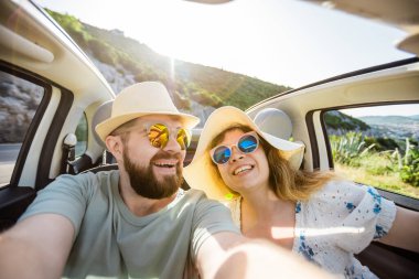 Romantik çift, okyanus ya da deniz kıyısındaki kiralık Cabrio arabasında akıllı telefon kamerasıyla selfie çekiyor, yaz tatilinin tadını çıkarıyor ve hafta sonları deniz kenarında cep telefonuyla dinlenirken fotoğraf çekiyor.