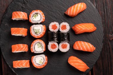 Large sushi set from top on black background. Assortment of various maki nigiri and rolls seafood soy sauce