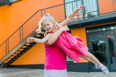 Mutlu anne dışarıda kollarının arasında daireler çizerek sallanıyor ve tatlı kızını döndürüyor. Neşeli, enerjik ve neşeli bir çocuk güneşli yaz tatilinde annesiyle kaynaşırken eğleniyor.