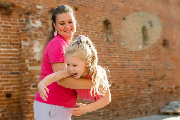 Stock image Blonde little girl with cochlear implant playing with her mother outdoor. Hear impairment deaf and health concept. Diversity and inclusion. Copy space.