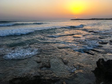 Kıbrıs 'ta gün batımı. Gün batımında kıyı manzarası. Akdeniz 'in gezinti güvertesi. Kıbrıs 'ın akşam manzarası