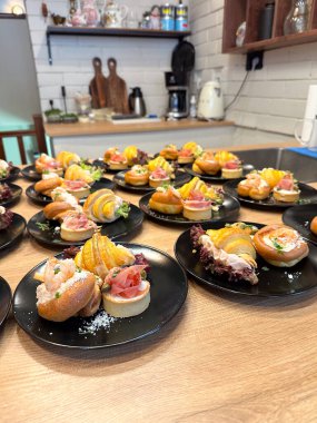 Gurme aperatifleri siyah tabaklara güzelce yerleştirilmiş. Renkli bir sunum ve çeşitli tatlar, lüks yemek deneyimi. Yemek ve büfe konsepti.