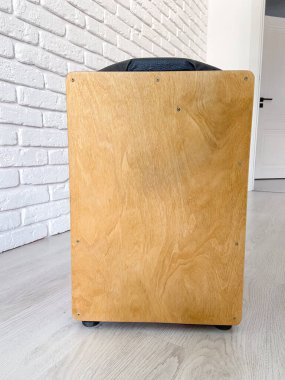 Cajon davulu, ahşap işçiliğini ön plana çıkaran, dokulu beyaz tuğla bir duvara karşı zarif bir şekilde oturur. Evde müzik ve hobi konsepti yaratmak için müzikal araç.