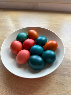 Bir kase canlı renkli Paskalya yumurtası ahşap bir yüzeyde duruyor. Güzel, neşeli ve neşeli bir atmosfer. Paskalya ve dini bayramlar.