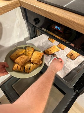 Fırından taze pişmiş hamur işleri çıkarılıyor, buharlı ve altın rengi kahverengi, yeşil bir tabakta servis edilmeye hazır. Kıtır kıtır hamurun aroması sıcacık mutfağı dolduruyor, sıcaklık hissi uyandırıyor ve...