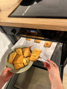 Fırından taze pişmiş hamur işleri çıkarılıyor, buharlı ve altın rengi kahverengi, yeşil bir tabakta servis edilmeye hazır. Kıtır kıtır hamurun aroması sıcacık mutfağı dolduruyor, sıcaklık hissi uyandırıyor ve...