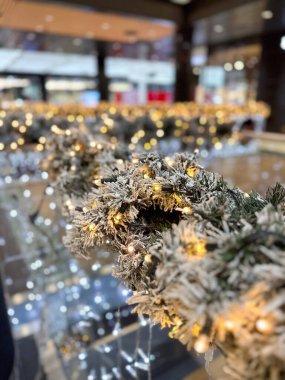 Yakın çekim, Noel şenlikli iç mekan ortamında parıldayan ışıklarla süslenmiş güzel bir çelenk yakalıyor. Ilık parıltı büyülü bir atmosfer yaratır. Tatil sezonu için mükemmel..